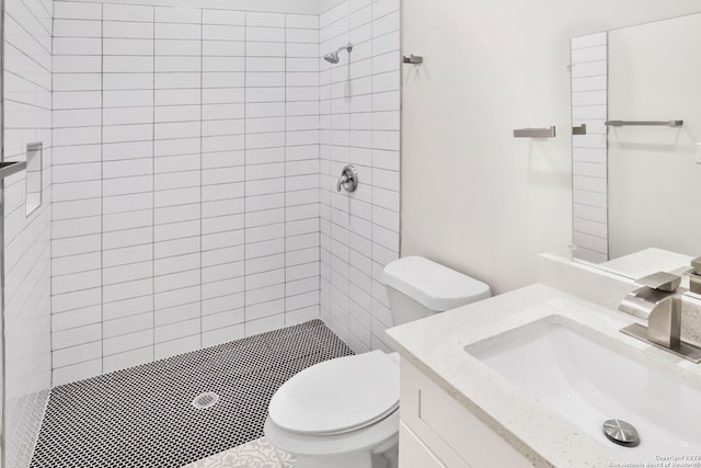 bathroom featuring large vanity, toilet, and a tile shower