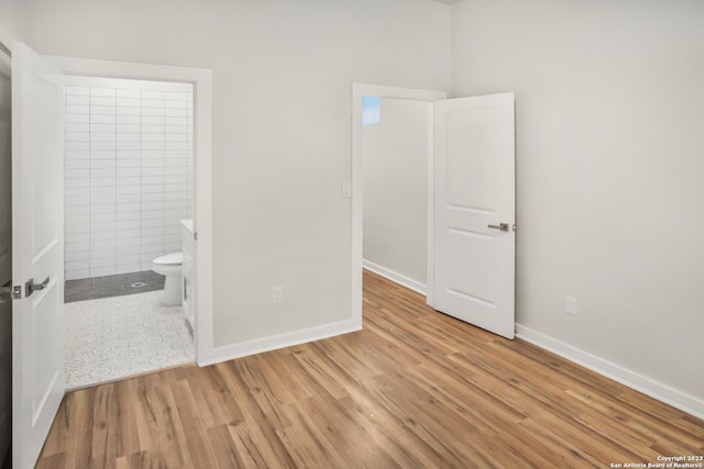 unfurnished bedroom with tile walls, ensuite bathroom, and light tile floors