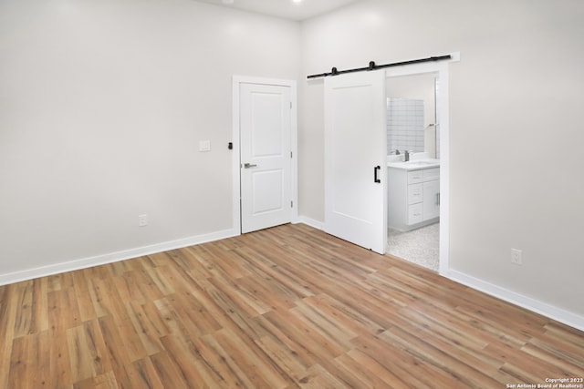 interior space featuring sink, connected bathroom, light wood-type flooring, and a barn door