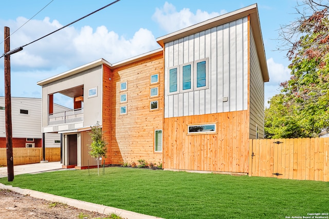 contemporary home featuring a balcony and a front lawn