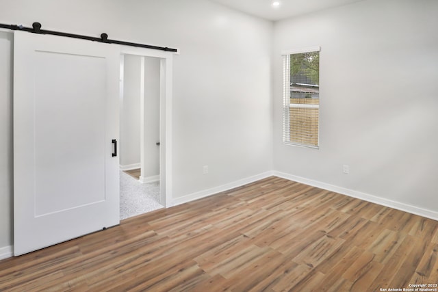 unfurnished room featuring a barn door and light hardwood / wood-style flooring