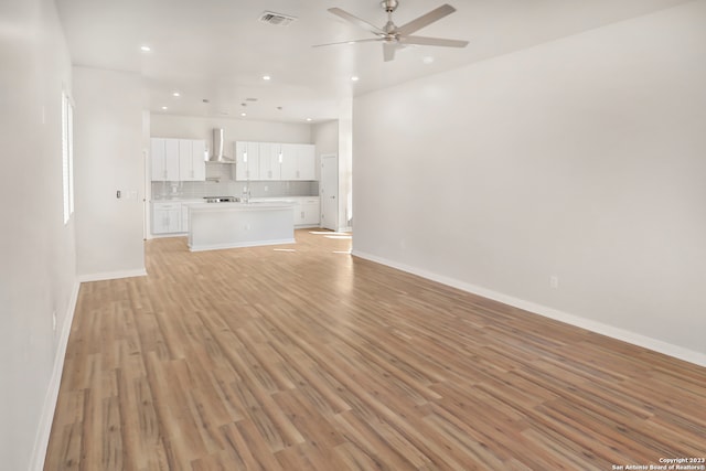 unfurnished living room featuring ceiling fan, sink, and light wood-type flooring