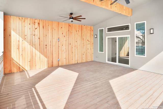 interior space with ceiling fan, lofted ceiling with beams, wooden walls, and light hardwood / wood-style floors