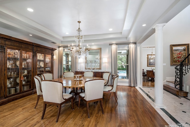 dining area featuring a raised ceiling, decorative columns, light tile floors, and an inviting chandelier