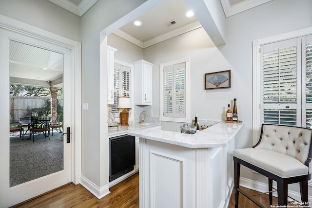 kitchen with white cabinets, a kitchen breakfast bar, wood-type flooring, and a wealth of natural light