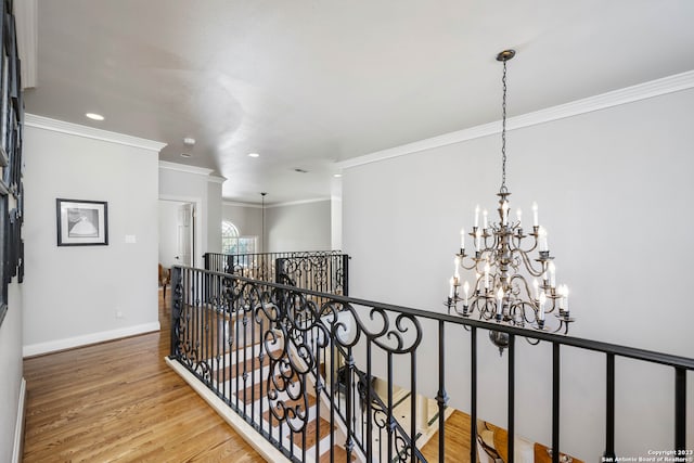 hall with an inviting chandelier, crown molding, and light wood-type flooring