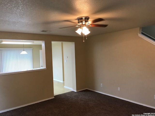 spare room with a textured ceiling, light colored carpet, and ceiling fan