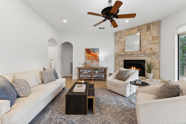 living room featuring ceiling fan and a stone fireplace