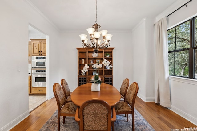 dining room featuring ornamental molding, a notable chandelier, and light wood-type flooring