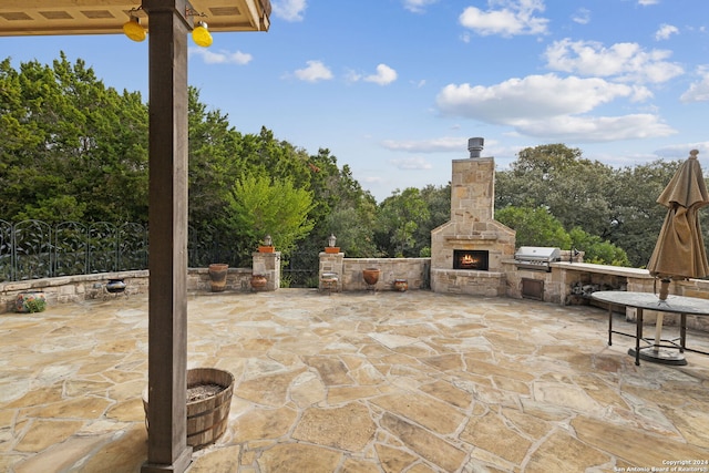 view of patio with an outdoor stone fireplace, a grill, and an outdoor kitchen