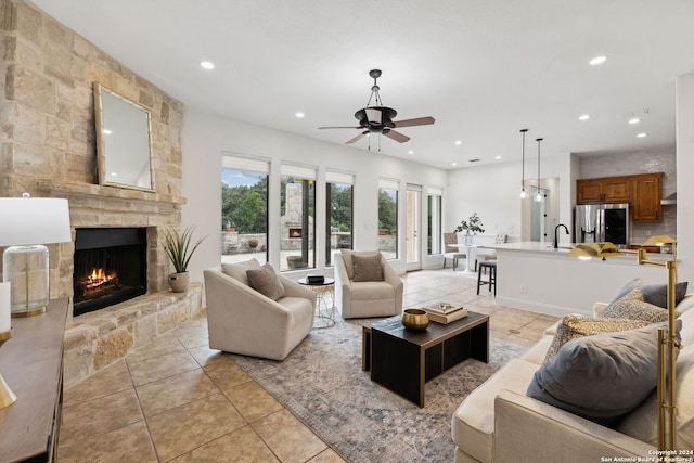 living room featuring a fireplace, ceiling fan, sink, and light tile patterned floors