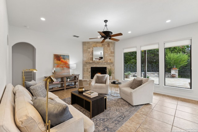 living room featuring a fireplace, light tile patterned floors, and ceiling fan