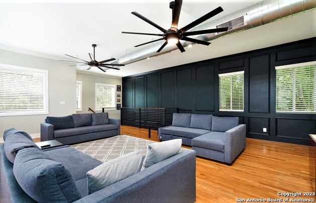 living room featuring wood-type flooring, ceiling fan, and ornamental molding