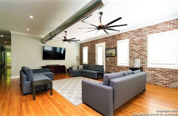 living room featuring ceiling fan, brick wall, and light hardwood / wood-style floors