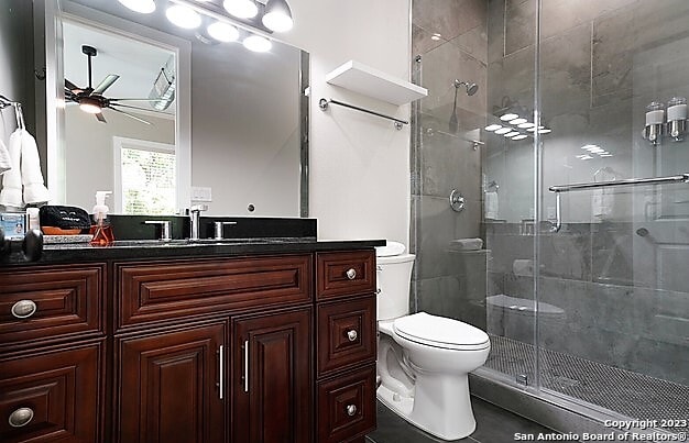 bathroom with an enclosed shower, tile patterned flooring, vanity, toilet, and ceiling fan