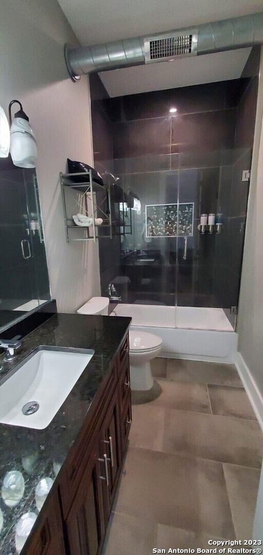 full bathroom with vanity, toilet, combined bath / shower with glass door, and tile patterned flooring