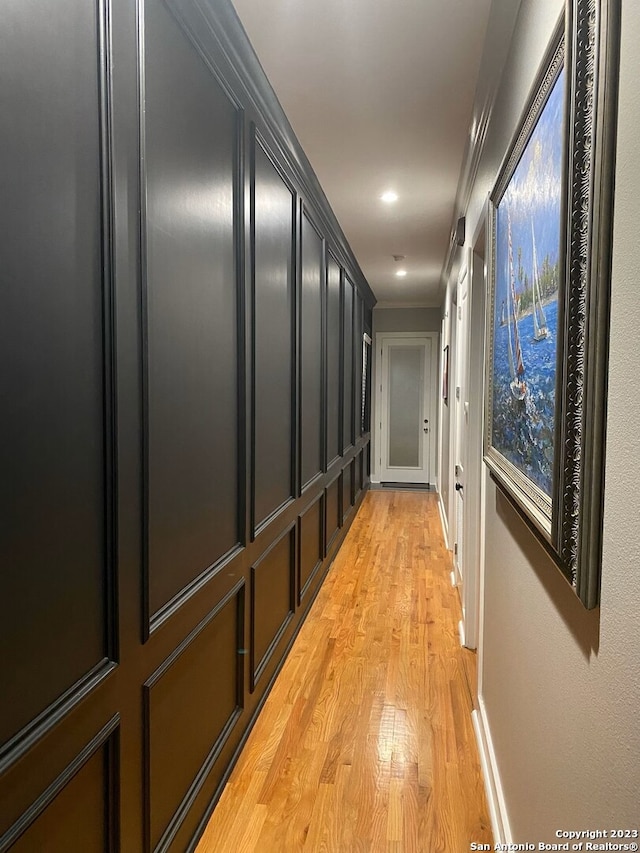 hallway with light hardwood / wood-style flooring and ornamental molding