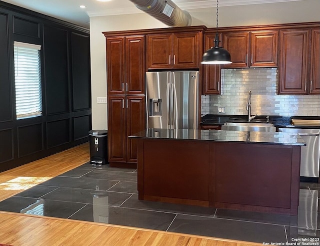 kitchen featuring hanging light fixtures, sink, tasteful backsplash, ornamental molding, and stainless steel appliances