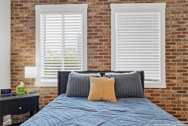 bedroom with multiple windows and brick wall