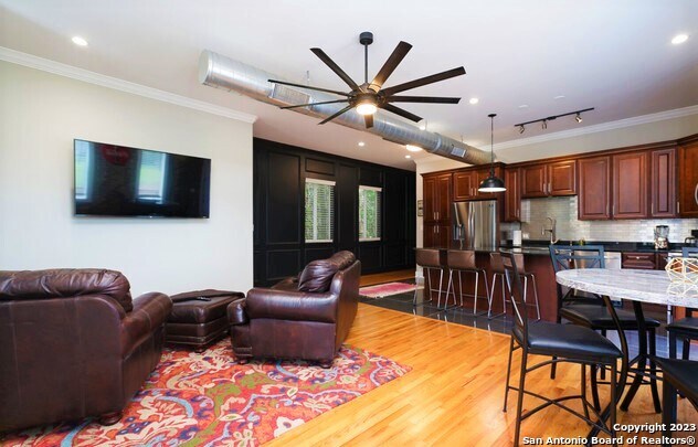 living room featuring hardwood / wood-style flooring, ceiling fan, crown molding, and rail lighting