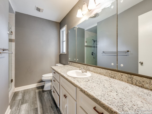 bathroom featuring toilet, a shower with door, large vanity, and hardwood / wood-style flooring