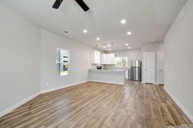 unfurnished living room featuring sink, ceiling fan, and light wood-type flooring