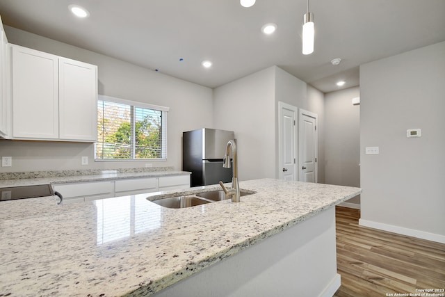 kitchen with light stone countertops, decorative light fixtures, white cabinetry, light wood-type flooring, and stainless steel refrigerator with ice dispenser