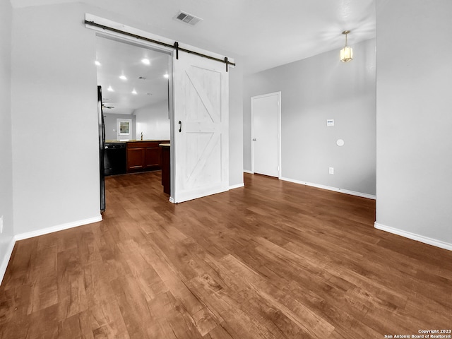 interior space with a barn door, ceiling fan, and dark hardwood / wood-style flooring