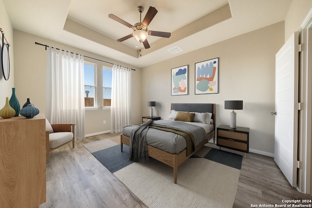 bedroom with a tray ceiling, ceiling fan, and hardwood / wood-style floors