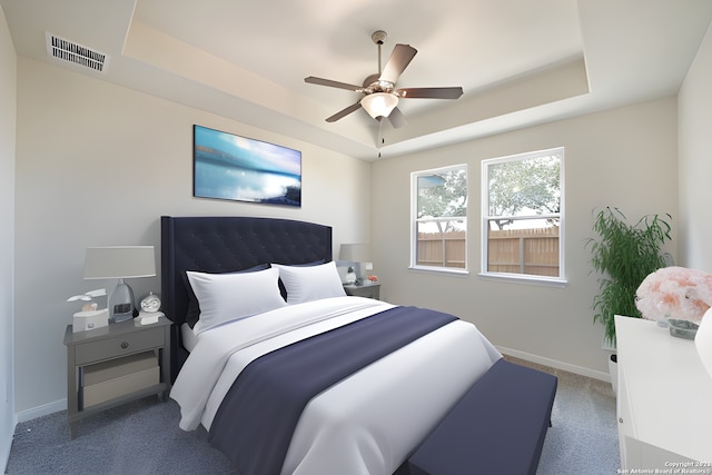 carpeted bedroom with a tray ceiling and ceiling fan