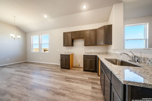 kitchen featuring light stone counters, vaulted ceiling, sink, light hardwood / wood-style flooring, and an inviting chandelier