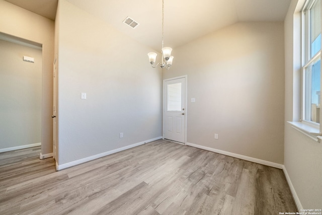 unfurnished room with light wood-type flooring, lofted ceiling, and an inviting chandelier