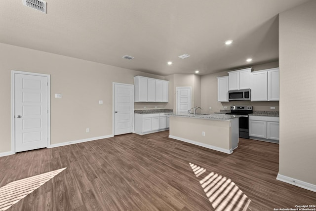 kitchen with a center island with sink, light stone countertops, white cabinets, and appliances with stainless steel finishes