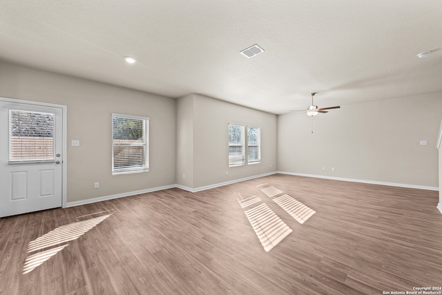 unfurnished living room with ceiling fan, hardwood / wood-style floors, and a textured ceiling