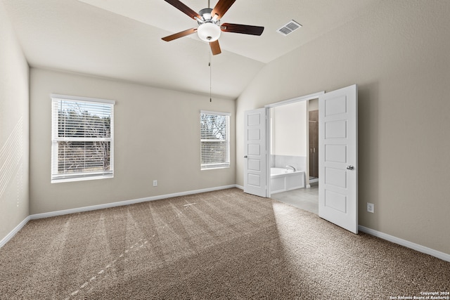 unfurnished bedroom with multiple windows, lofted ceiling, light carpet, and ensuite bath