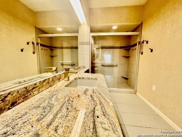 bathroom with tile flooring, walk in shower, and vanity