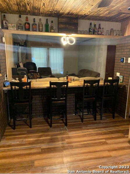 dining room with wood ceiling, hardwood / wood-style floors, and bar area