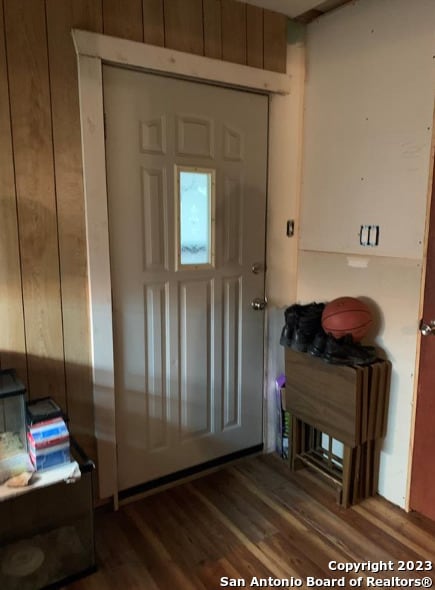 entryway with hardwood / wood-style floors and wooden walls