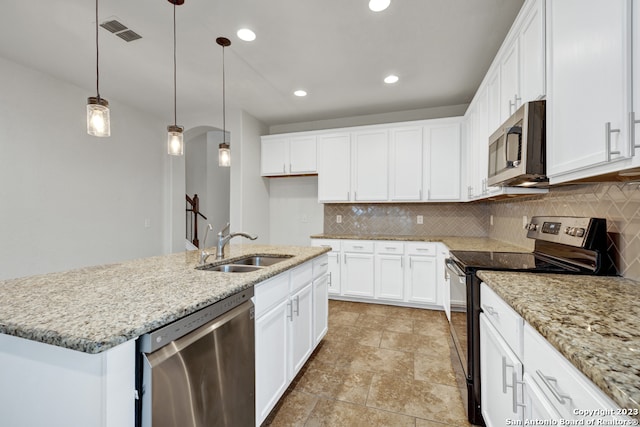 kitchen with a center island with sink, decorative light fixtures, backsplash, and stainless steel appliances