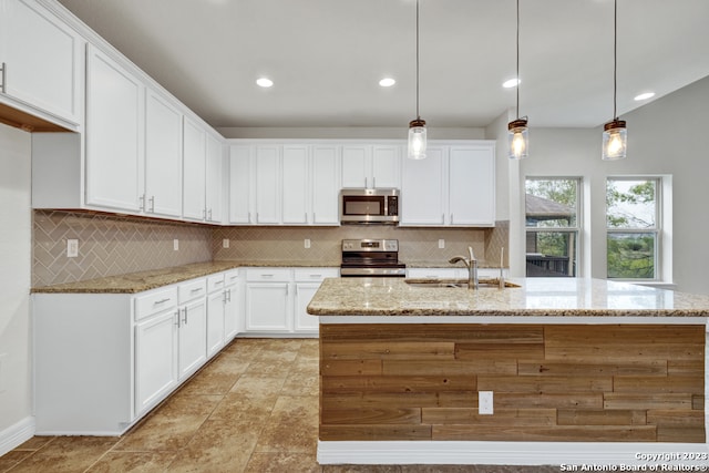 kitchen with appliances with stainless steel finishes, pendant lighting, tasteful backsplash, and sink