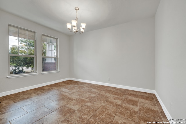 spare room with light tile floors and an inviting chandelier