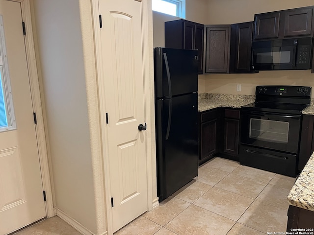 kitchen with light tile floors, light stone counters, and black appliances