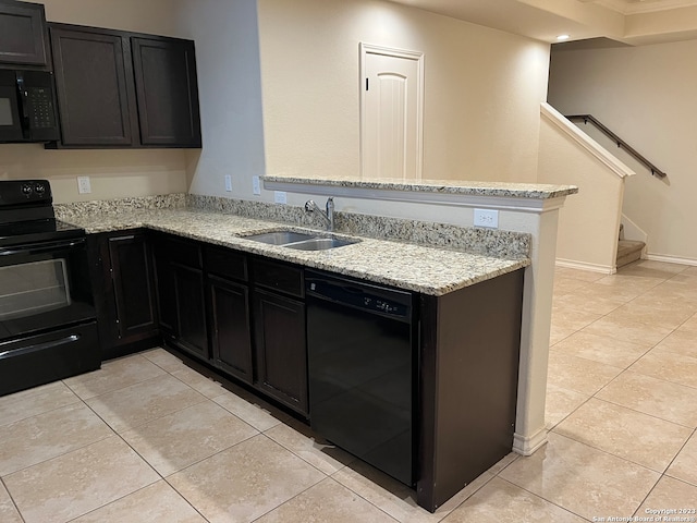 kitchen with light stone counters, kitchen peninsula, black appliances, sink, and light tile flooring