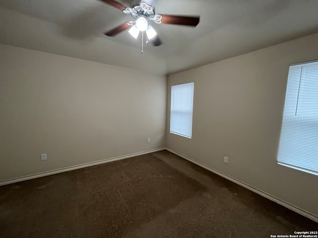 spare room featuring ceiling fan and dark carpet