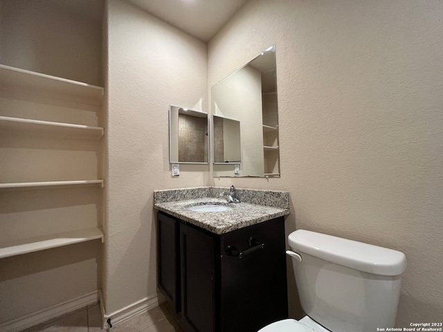 bathroom featuring toilet, tile floors, and vanity