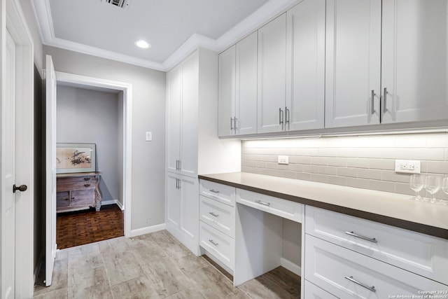 kitchen featuring light parquet floors, white cabinetry, ornamental molding, and tasteful backsplash