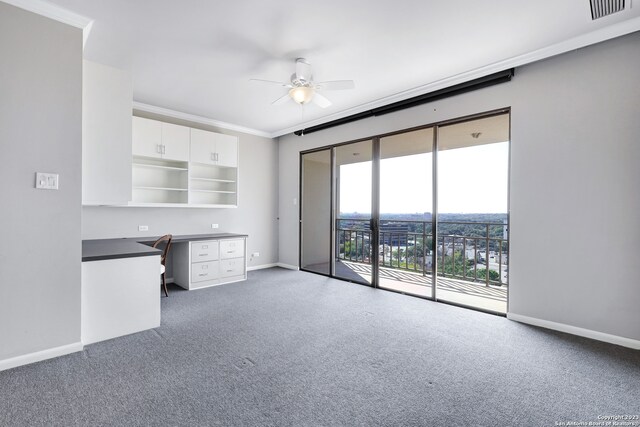 interior space with ceiling fan, built in desk, ornamental molding, and white cabinetry