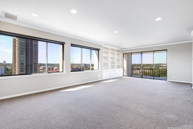 carpeted spare room featuring built in shelves, a healthy amount of sunlight, and ornamental molding