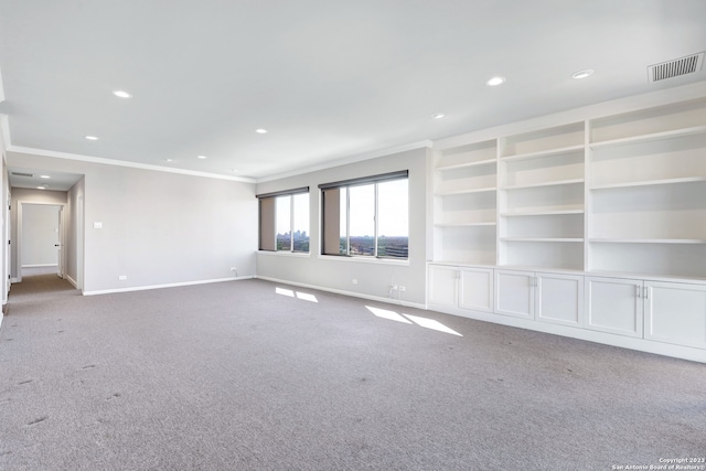 carpeted empty room with crown molding and built in shelves