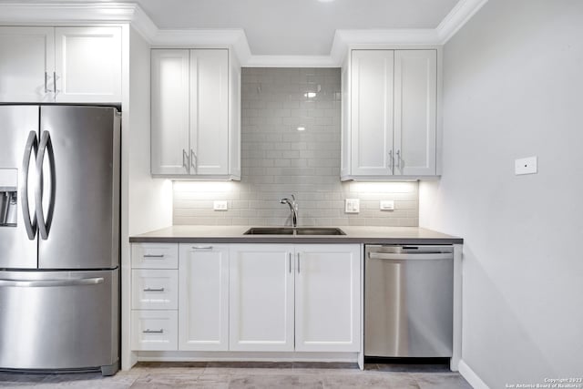 kitchen with tasteful backsplash, stainless steel appliances, sink, ornamental molding, and white cabinets